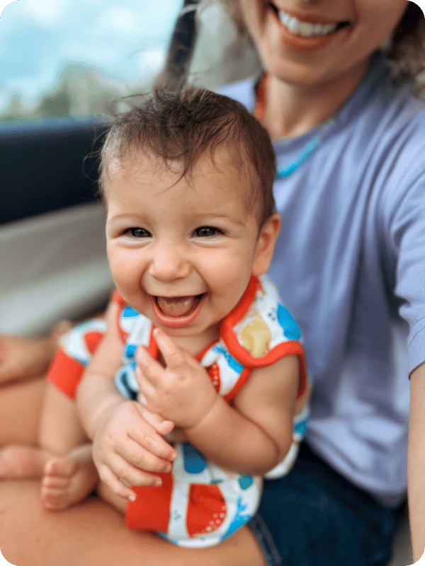6 month old smiles and plays on mom's lap
