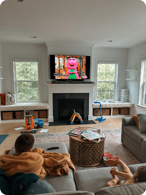 A toddler and a preschooler watch Barney on TV
