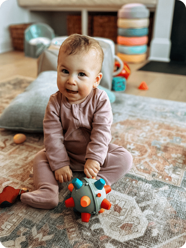 baby wearing cotton pajamas playing with toys