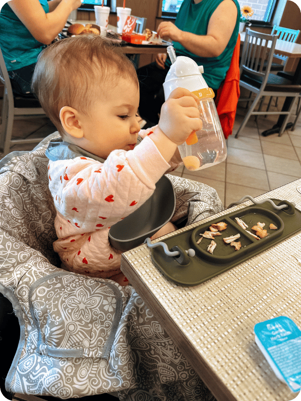 Baby eats a chicken nugget cut into age-appropriate slices.